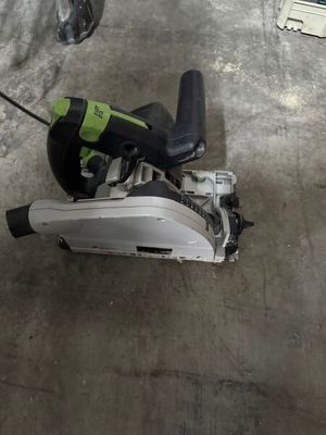 une scie circulaire filaire posée par terre dans un garage