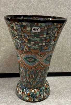 un vase posé par terre, sur lequel est accrochée une étiquette