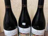 three bottles of wine sitting on top of a wooden table