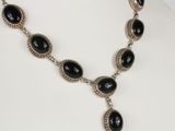 a necklace with black stones and silver beads on a mannequin