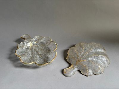 deux plats en argent décorés de feuilles, posés sur une table