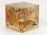 a gold cube with a painting on it on a white surface