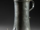 une cafetière ancienne en métal argenté, surmontée d'un oiseau