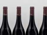 six bottles of red wine lined up in a row on a table