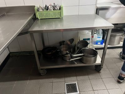 une femme debout dans une cuisine, avec des casseroles et des poêles posées sur le plan de travail