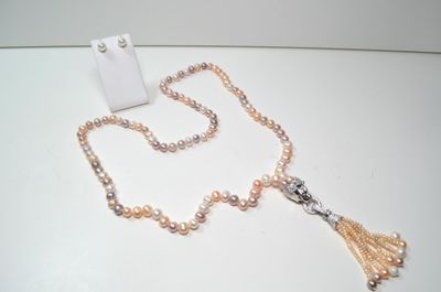 collier avec des perles et un pompon posé sur une table blanche