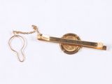 a gold tie bar with a chain attached to it