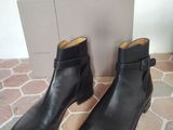 a pair of black leather boots on a tiled floor next to a box