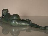 statue of a boy laying on his back on a glass table