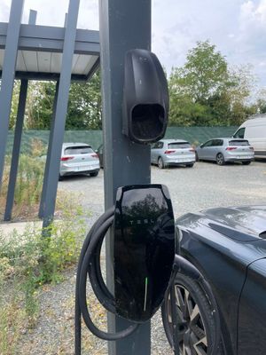 une voiture noire branchée sur une borne de recharge électrique