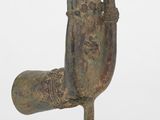 une vieille statue en bronze représentant une main, posée sur un socle en bois