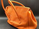 an orange leather handbag on a black background