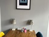 une table en bois avec des chaises jaunes et bleues et un tableau accroché au mur