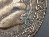 a close up of a bronze medallion with a man ' s face