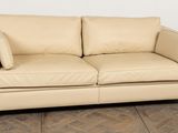 a tan leather couch with pillows on it in a room