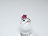 a ring with a red stone on it sitting on a glass