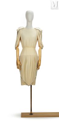 une photo d'un mannequin portant une robe beige, posé sur un socle en bois