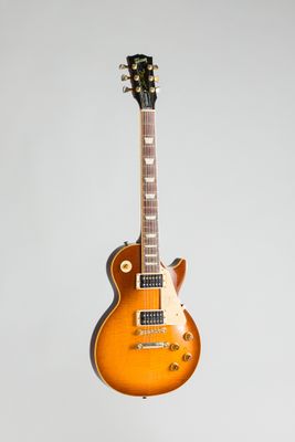 une guitare électrique orange posée sur un support en bois