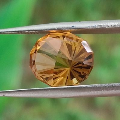 un gros plan d'un diamant jaune tenu par une paire de pinces