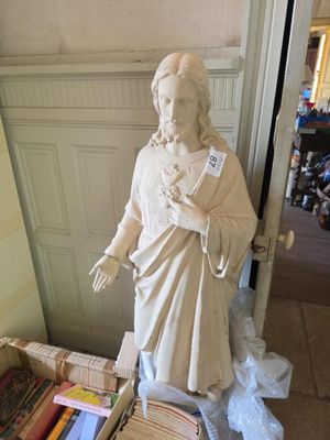 une statue représentant un homme tenant un livre à côté d'une pile de livres