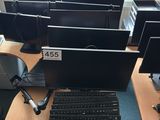 many computer monitors and keyboards on the desk