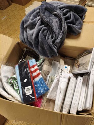 une boîte remplie de vêtements et une couverture posée par terre