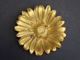 broche en forme de fleur plaquée or sur un fond noir