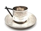 a silver cup and saucer on a silver plate