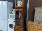 a tall wooden cabinet with a clock on top of it next to a washer and dryer