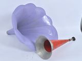 une corne violette et un cône rouge posés sur une table blanche