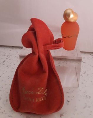 un flacon de parfum dans une pochette en velours rouge, avec un bouchon doré