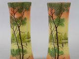 pair of vases with trees painted on them sitting on a table