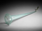 a green glass trumpet shaped object sitting on top of a table