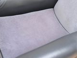 grey leather chair in a corner of a room with a rug on the floor