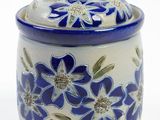 a blue and white jar with flowers on it on a white surface
