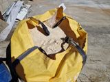un grand sac de sable posé par terre à côté d'une poubelle bleue