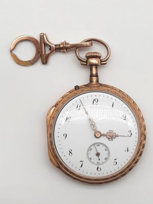 une montre de poche en or à laquelle est accrochée une clé sur le côté