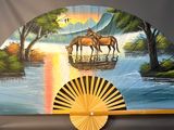 a fan with a painting of two horses on it