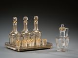 a silver tray with four bottles and a glass decanter