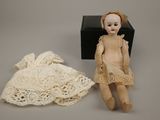 an image of a doll is sitting next to a dress on a table