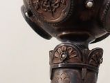 a silver vase that has a bird on top of it