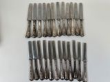 eight silverplated knives and six knives are laid out on a table