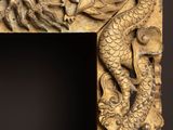 an ornate carved frame with a dragon and a bird on it