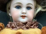 a close up of a doll wearing a brown hat