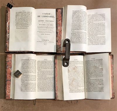 trois livres ouverts posés sur une table, avec une clé au milieu