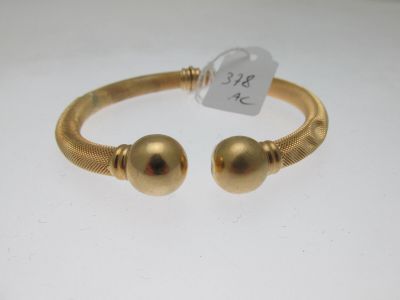 un bracelet en or orné de deux boules et muni d'une étiquette de prix