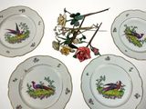 four plates decorated with birds and flowers on a white surface