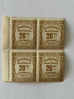 quatre vieux timbres-poste collés sur un morceau de papier posé sur une surface blanche