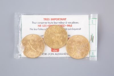 three gold coins in a plastic bag on a white surface