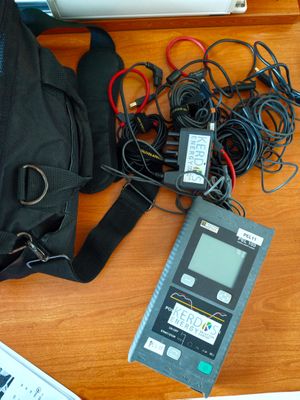un sac noir posé sur une table, à côté d'un ordinateur portable et d'autres appareils électroniques